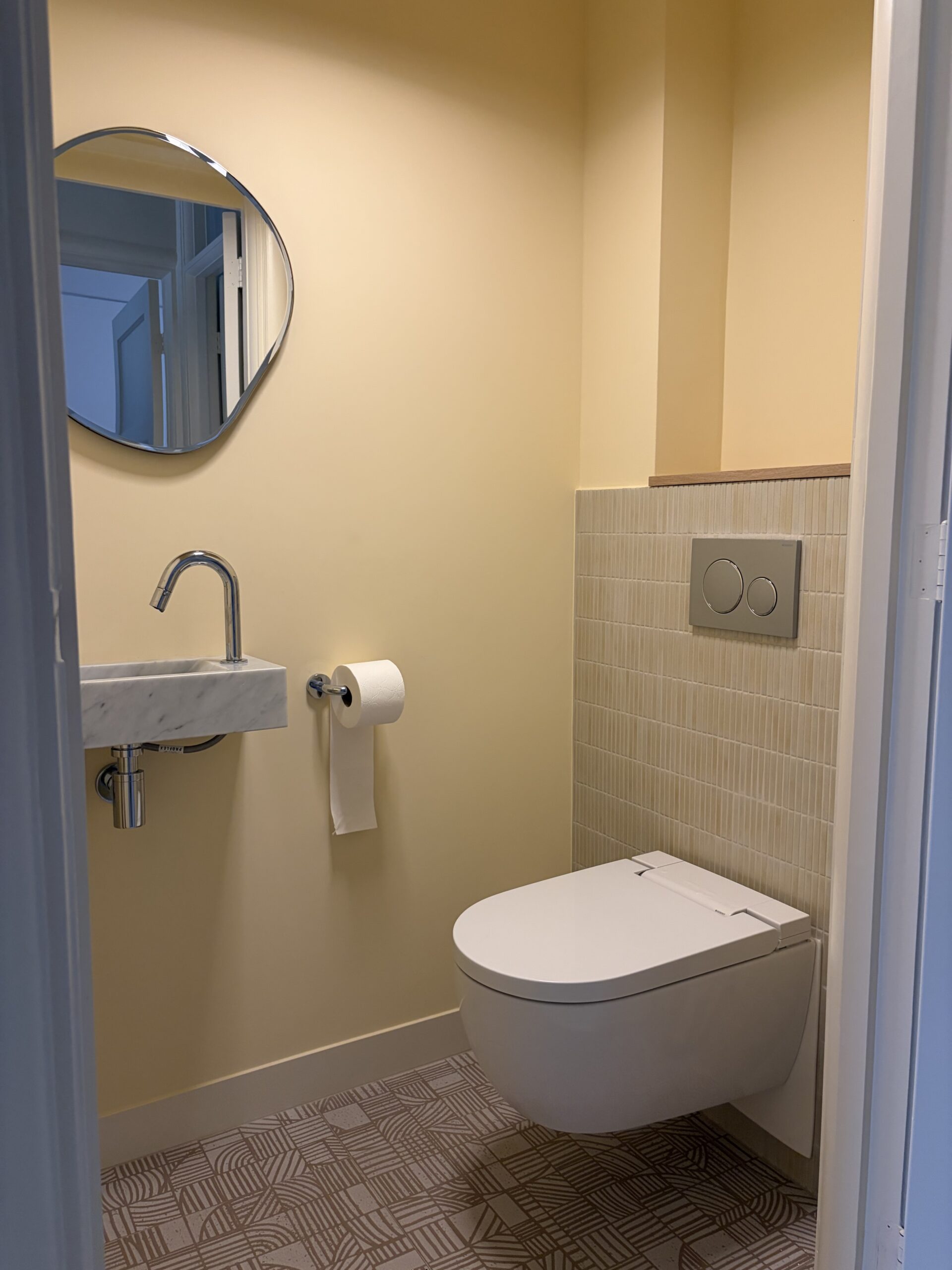 Toilet beneden met marmeren fonteintje en ronde spiegel